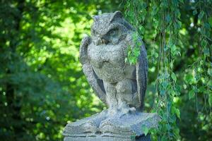 scultura di gufo seduta su libro nel verde le foglie di un' giardino come un' parte di un' grande recinto foto