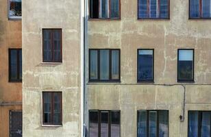 parete di Marrone edificio con stailess acciaio acqua tubo e molti diverso finestre con vario oggetti e persone dentro foto