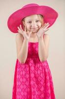 poco ragazza con rosa vestito e cappello foto