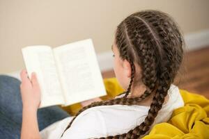 adolescenziale ragazza con trecce lettura libro su giallo beanbag sedia foto