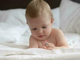 bambino su letto giocando con perline foto