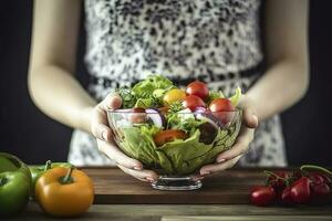 un' Visualizza di un' giovane donna di mani Tenere un' bicchiere ciotola pieno di un' salutare misto insalata, creare ai foto