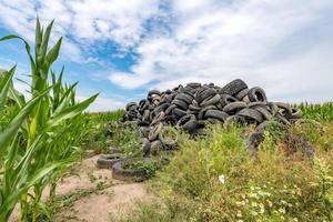 vecchi pneumatici per auto rotti ammucchiati su una montagna in un campo di grano foto