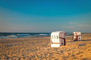 sedie a sdraio stanno al tramonto su una spiaggia sul Mar Baltico con il mare foto