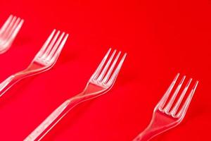 Close-up di forchette di plastica trasparente su uno sfondo rosso