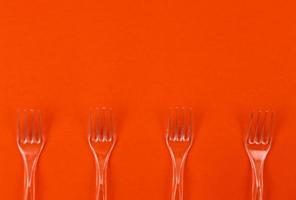 Close-up di forchette di plastica trasparente su uno sfondo arancione