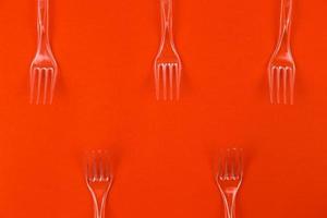 Close-up di forchette di plastica trasparente su uno sfondo arancione foto