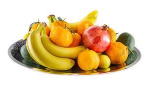 vassoio di frutta e verdura assortito di banane, melograno, limone, mandarino e avocado.