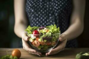 un' Visualizza di un' giovane donna di mani Tenere un' bicchiere ciotola pieno di un' salutare misto insalata, creare ai foto