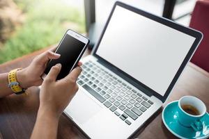 Close up man holding smartphone e utilizzando un laptop foto