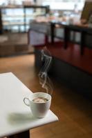 tazza di caffè bianco sul tavolo all'interno del caffè foto