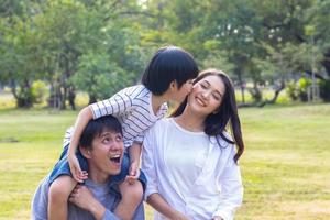 famiglia asiatica gode di sedersi nel parco durante le vacanze autunnali foto