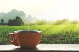 caffè caldo nero caldo con fumo su un tavolo di legno con un paesaggio di natura con la montagna al mattino foto