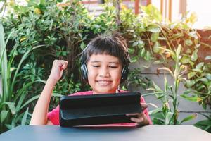 ragazzo carino asiatico che gioca giochi sul tablet foto