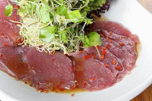 carpaccio di pesce con olive ana insalata servita su un piatto bianco