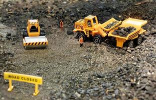 i lavoratori del giocattolo nel diorama della costruzione di strade caricano le rocce in un camion foto