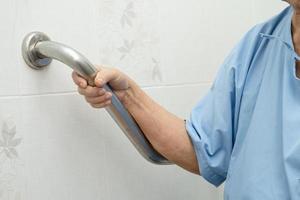 il paziente asiatico della donna della signora anziana senior o anziana usa la sicurezza della maniglia del bagno della toilette nel concetto medico sano del reparto infermieristico dell'ospedale foto