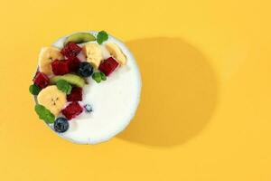 Yogurt ciotola con fresco frutta guarnizione e menta le foglie foto