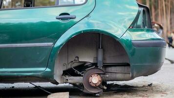 un' auto senza un' posteriore ruota su il lato di il strada. il posteriore centro di un' auto senza un' ruota. un vecchio auto senza ruote nel un' parcheggio lotto con rubato ruote e fari. auto su mattoni. foto