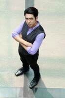 sud-est asiatico giovane ufficio attività commerciale uomo indossare veste In piedi Guarda su attraversare braccio fiducioso espressione all'aperto premesse pavimento foto