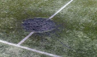 un' buco nel il terra a partire dal un' cannone conchiglia esplosione pieno con fresco terra a un' calcio stadio. bombardamento cratere nel il città. terreno di gioco. guerra nel Ucraina. distruzione di civile infrastruttura. foto