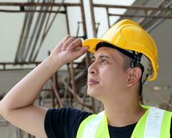 Sud est asiatico giovane malese uomo indossare giallo sicurezza casco veste guardare su foto