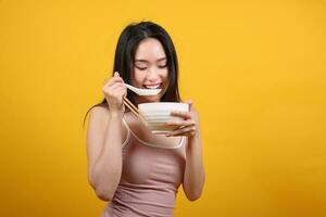 bellissimo giovane Sud est asiatico donna Tenere chines vuoto bacchette Cinese la minestra cucchiaio ciotola utensile fare finta recitazione in posa vedere mangiare gusto odore alimentazione offrire soddisfazione delizioso giallo arancia sfondo foto