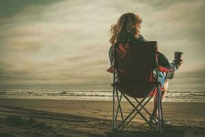 donna con caffè nel sua mano godendo gratuito tempo su un' spiaggia foto