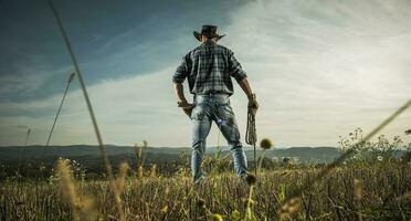 americano cowboy sorvegliare il suo campagna terreni agricoli foto