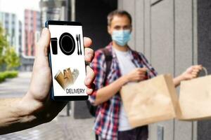 consegna cibo servizio a casa. uomo Corriere consegnato il ordine no nome Borsa con cibo. mano Tenere inteligente Telefono con cibo in linea dispositivo su schermo foto