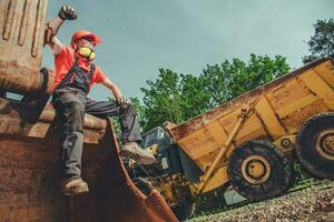 caucasico costruzione lavoratore seduta e riposo su superiore di retroescavatore. foto