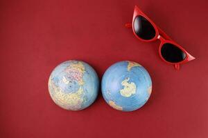 rosso occhiali occhiali da sole mondo atlante globo carta geografica nord Sud polo su rosso carta sfondo foto