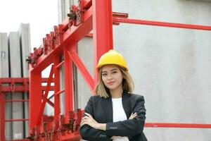 asiatico donna Cinese malese lavoratore ingegnere gestione difficile cappello sicurezza casco a costruzione luogo posa Guarda fiducioso foto