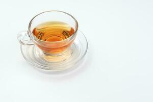 chiaro leccapiedi tè nel un' trasparente bicchiere tazza piattino cucchiaio su bianca sfondo foto