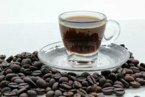 piccolo bicchiere trasparente caffè tazza piattino pieno caffè fagioli foto