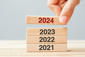 2024 bloccare al di sopra di 2023 e 2022 di legno edificio su tavolo sfondo. attività commerciale pianificazione, rischio gestione, risoluzione, strategia, soluzione, obiettivo, nuovo anno nuovo voi e contento vacanza concetti foto