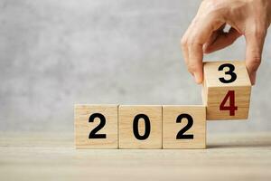 mano capovolgimento bloccare 2023 per 2024 testo su tavolo. risoluzione, strategia, Piano, obiettivo, motivazione, riavviare, attività commerciale e nuovo anno vacanza concetti foto