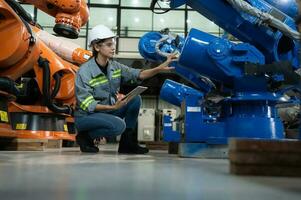 un' femmina ingegnere installa un' programma su un' robotica braccio nel un' robot magazzino. e test il operazione prima invio il macchina per il cliente. foto