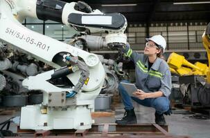 un' femmina ingegnere installa un' programma su un' robotica braccio nel un' robot magazzino. e test il operazione prima invio il macchina per il cliente. foto