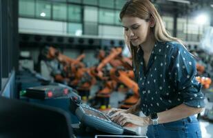 un' femmina ingegnere installa un' programma su un' robotica braccio nel un' robot magazzino. e test il operazione prima invio il macchina per il cliente. foto