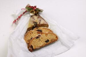 Natale natale decorazione ornamento campana regalo carta avvolgere affettato Stollen frutta torta cibo su bianca sfondo foto