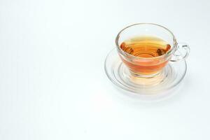 chiaro leccapiedi tè nel un' trasparente bicchiere tazza piattino cucchiaio su bianca sfondo foto