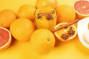 fresco arancia cannella stella anice Chiodo di garofano Spezia succo nel bicchiere su bianca giallo sfondo foto