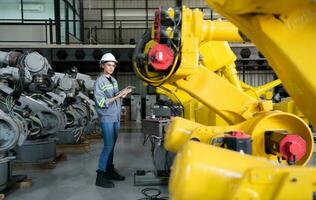 un' femmina ingegnere installa un' programma su un' robotica braccio nel un' robot magazzino. e test il operazione prima invio il macchina per il cliente. foto