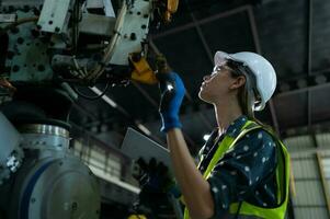 un' femmina ingegnere installa un' programma su un' robotica braccio nel un' robot magazzino. e test il operazione prima invio il macchina per il cliente. foto