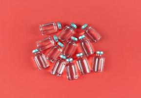 un sacco di fiale con medicina liquida su sfondo rosso