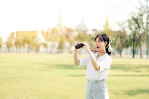 ritratto di asiatico donna viaggiatore utilizzando telecamera. Asia estate turismo vacanza concetto con il mille dollari palazzo nel un' sfondo a bangkok, Tailandia foto