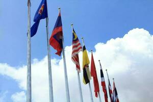molte delle bandiere dell'Asean nei colori variopinti sospinti dalla forza del vento che sventola su un palo davanti a un hotel in thailandia su uno sfondo con nuvole e cieli azzurri. foto