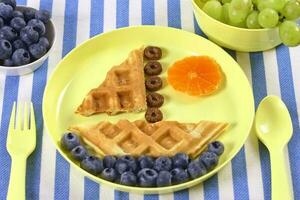 creativo idea per bambini prima colazione. barca di cialde con mirtilli e mandarini. foto