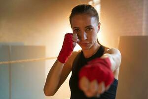 donne se stesso difesa ragazza potenza. forte donna combattente punzonatura con rosso boxe impacchi gli sport protettivo bende. ragazza punzonatura formazione pugni guardare concentrato dritto. in forma corpo allenamento. foto